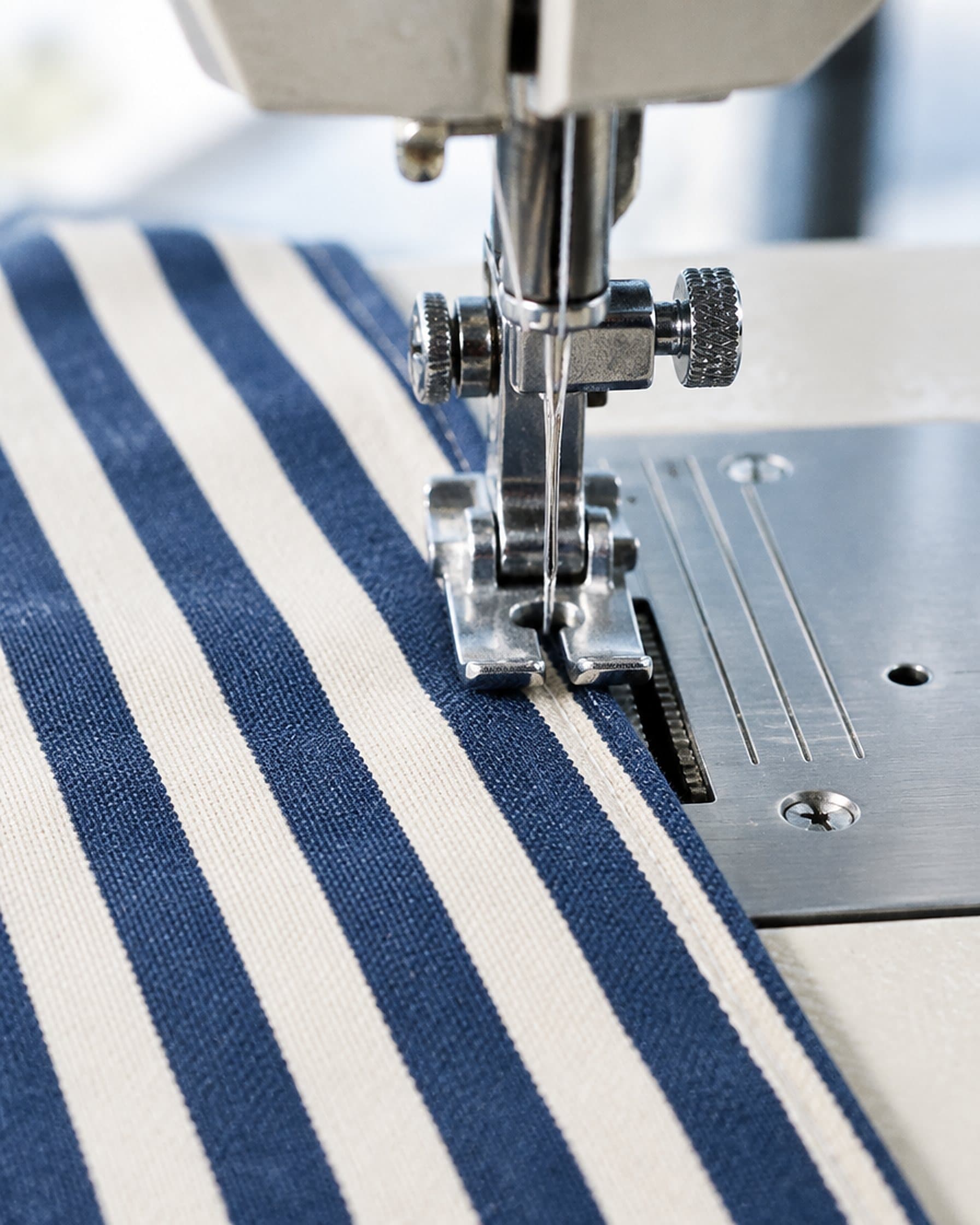 Striped cloth under the presser foot of a sewing machine.